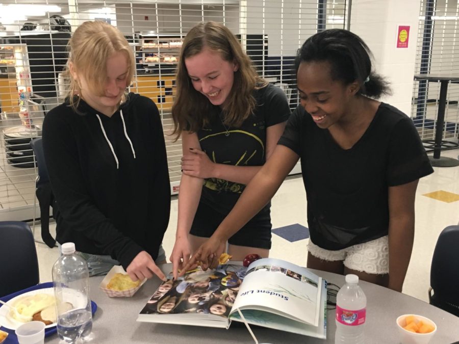 Three freshman, Alysa Hand, Kinslee Keatts and Natalie Sutherlin enjoy looking through the new yearbook.