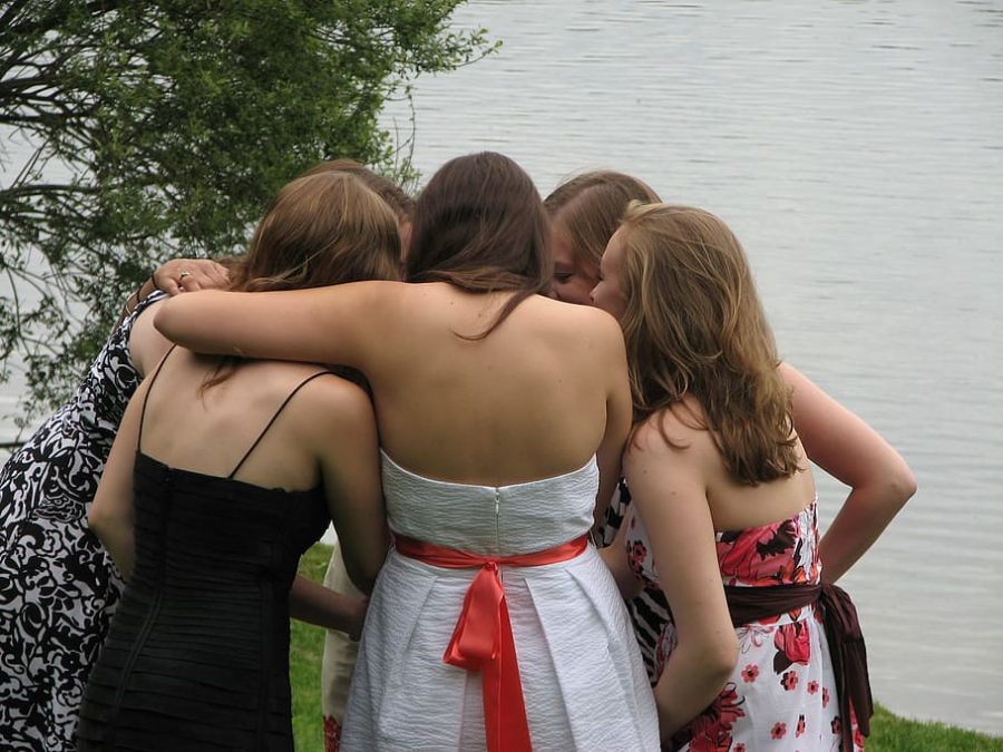 Girls are huddled together, hugging and hyping each other up for their school dance.