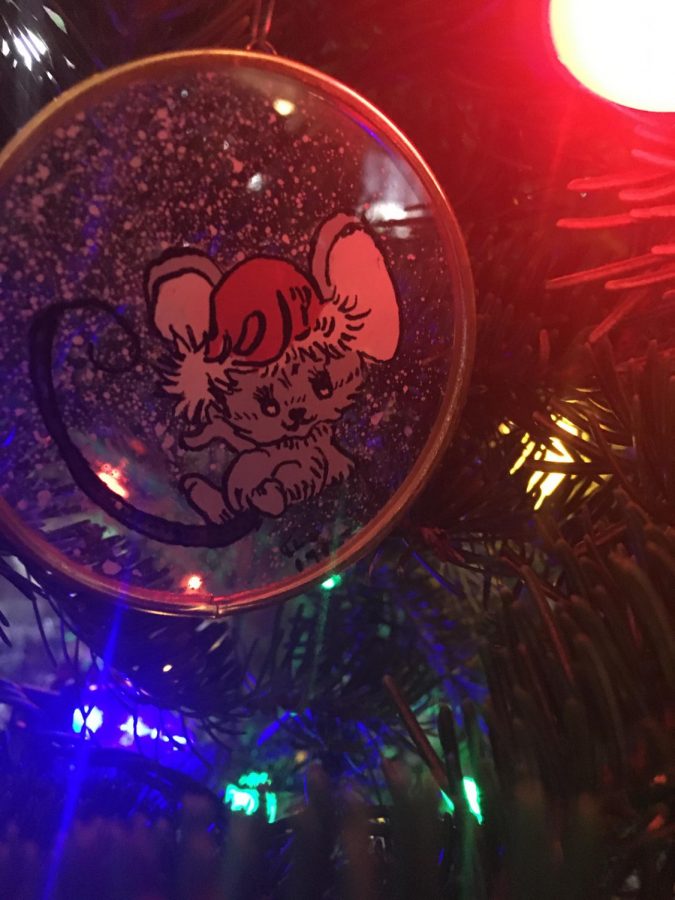 An ornament of a mouse hangs from the Christmas tree.